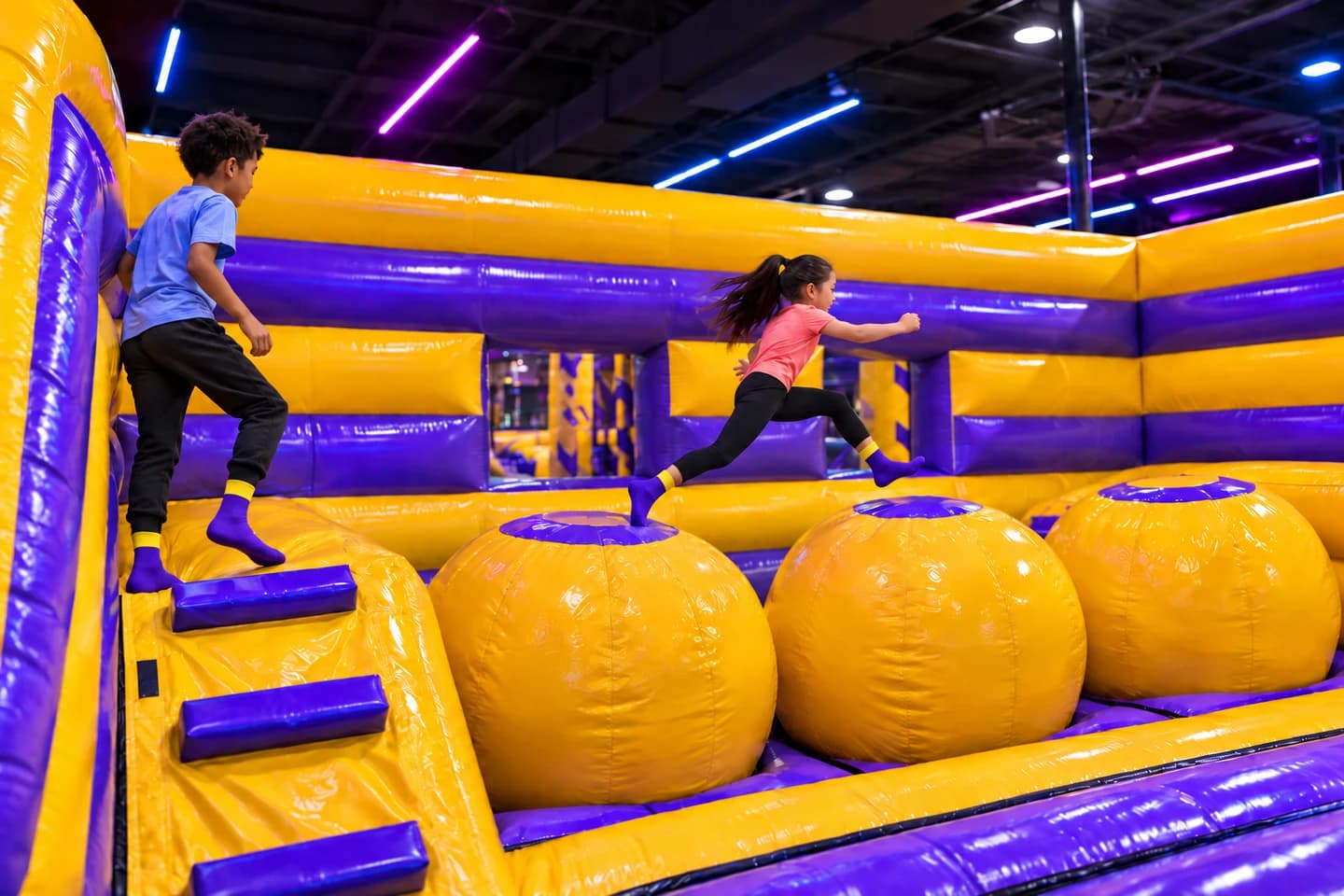 Children crossing large yellow inflatable ball obstacles